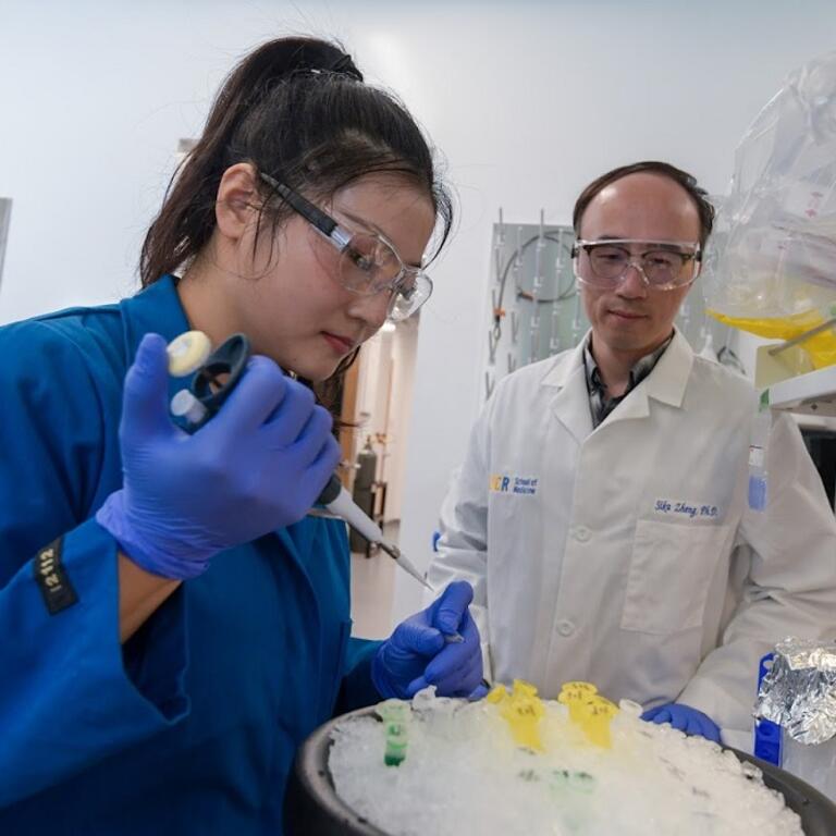 Student preparing samples as Dr. Zheng looks on.