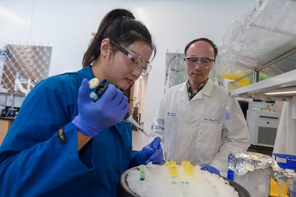 Student preparing samples as Dr. Zheng looks on.